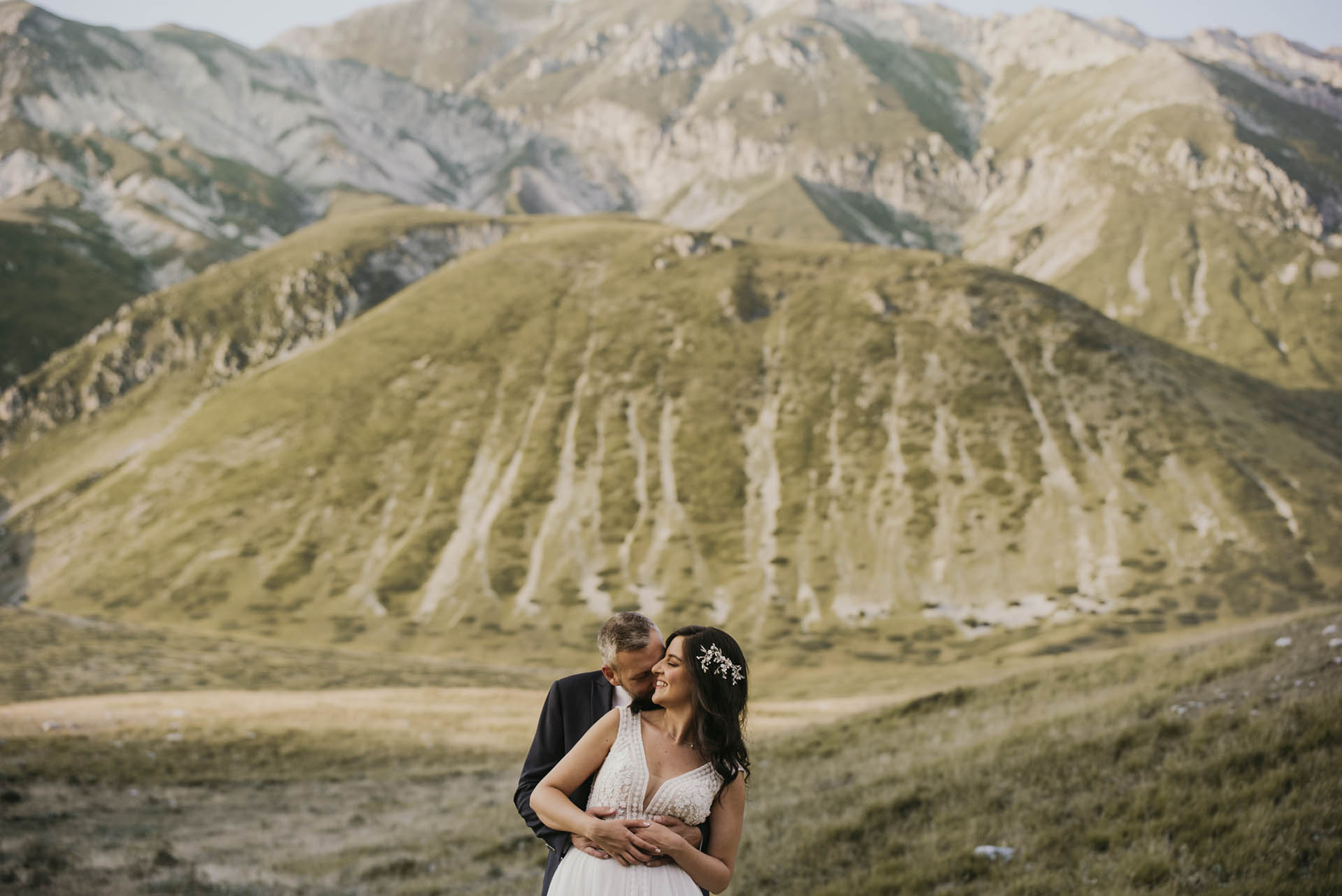 Una coppia di sposi abbracciata, sullo sfondo un paesaggio montuoso in una delle più belle location di matrimonio in Abruzzo